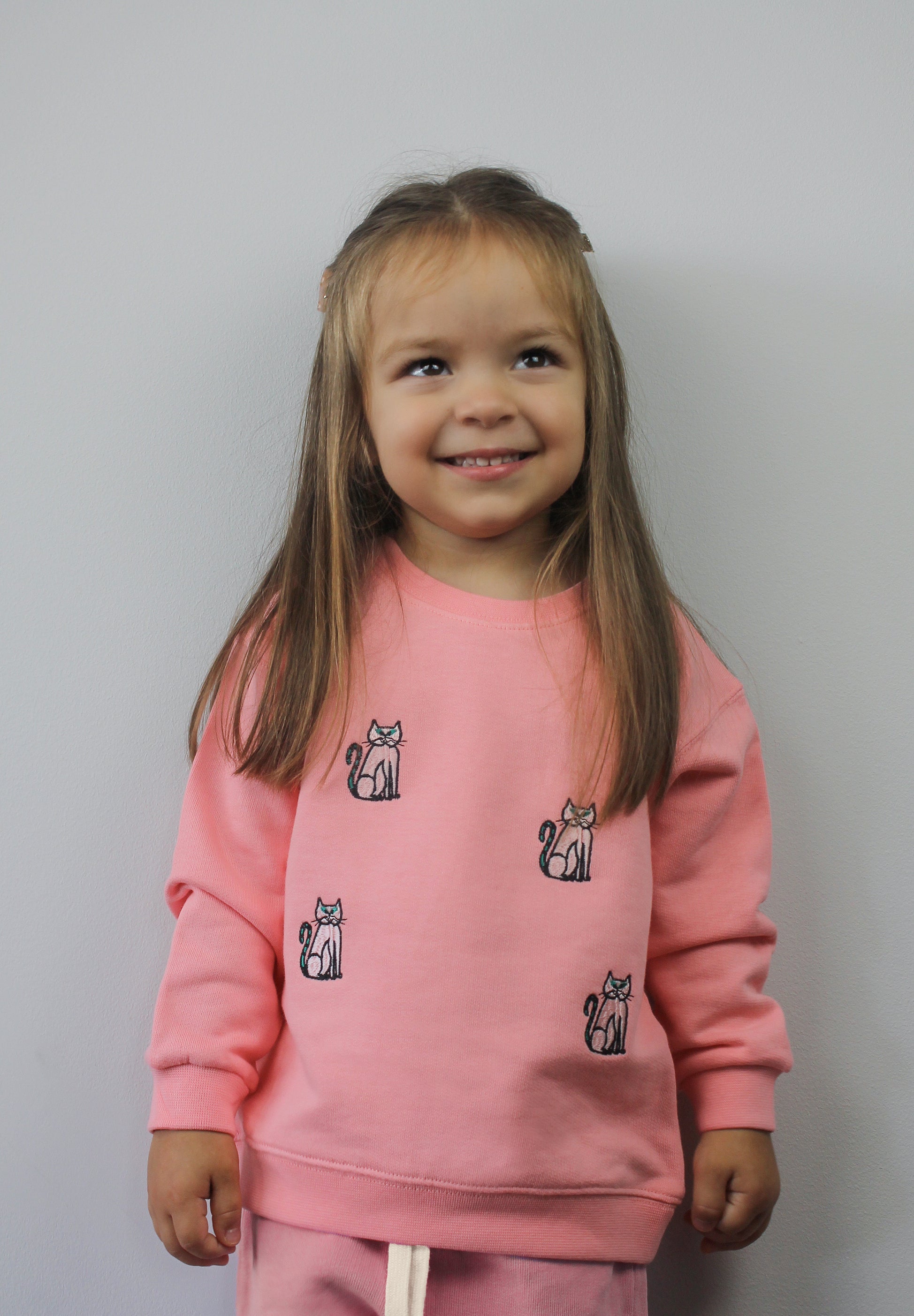 Child wearing pink kids’ tracksuit bottoms with cat design