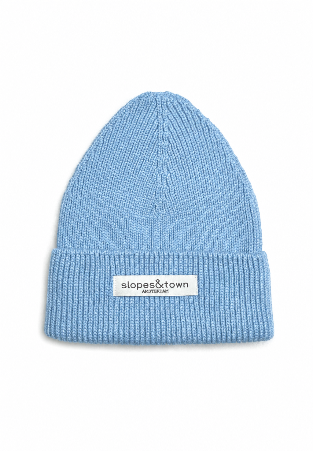 A light blue ribbed knit beanie hat with a white rectangular brand patch on the front cuff that reads 'slopes&town amsterdam'. The beanie is photographed flat against a clean white background.