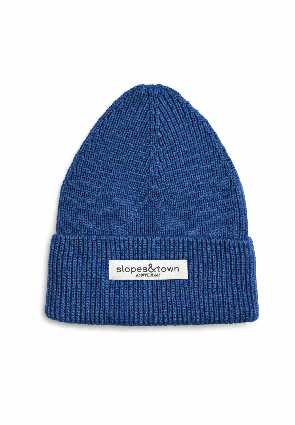 A blue ribbed knit beanie hat with a folded cuff and a white rectangular label reading 'slopes&town AMSTERDAM' on the front