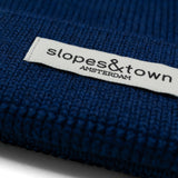 Kinderbeanie van merinowol in marineblauw, met ribgebreide textuur en omgeslagen boord.