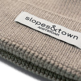 Close-up of Slopes and Town Amsterdam woven label on beige kids merino wool beanie