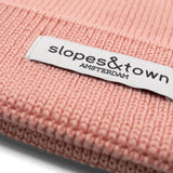 Close-up of Slopes and  Town Amsterdam woven label on soft pink kids merino wool beanie