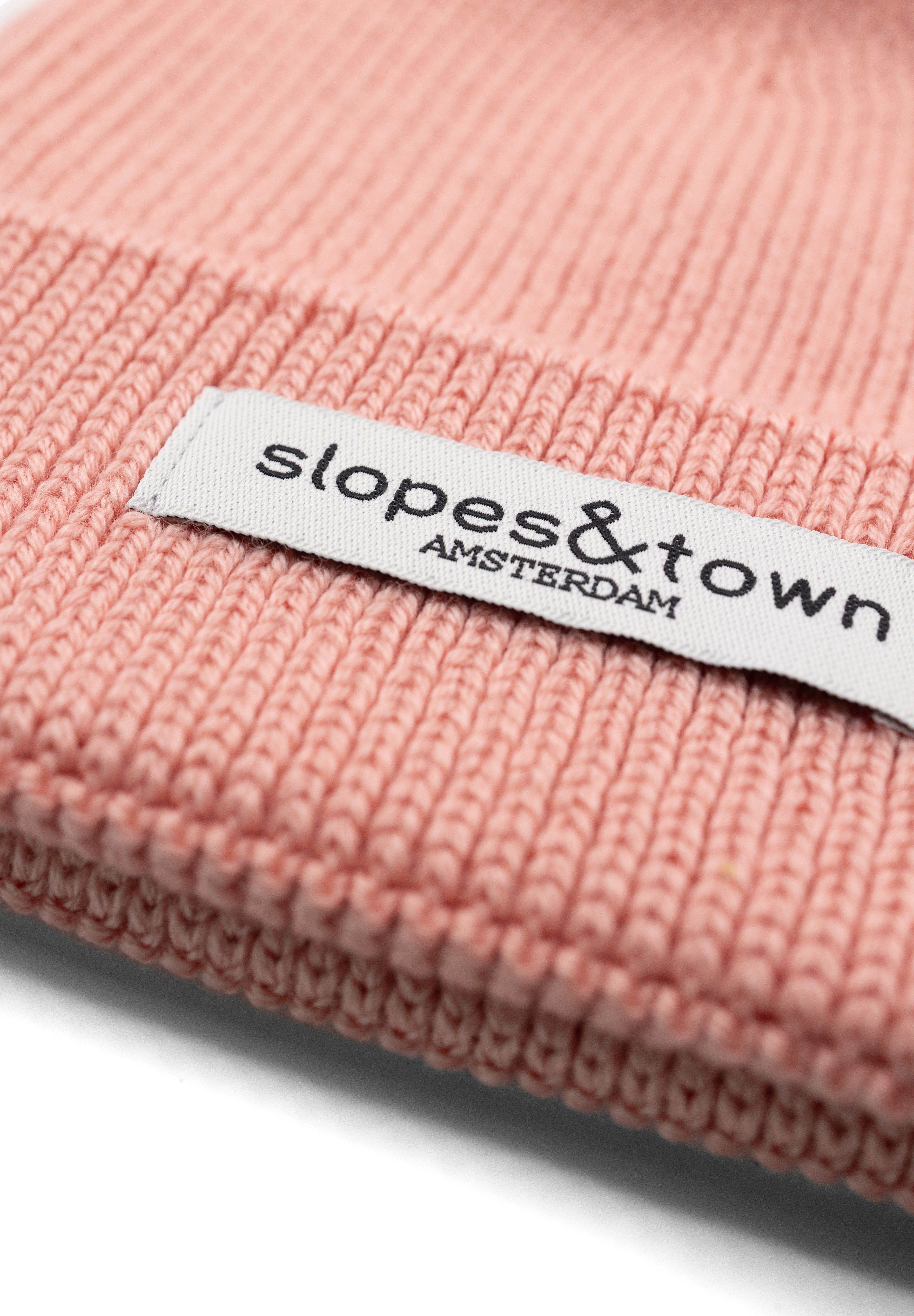 Close-up of Slopes and  Town Amsterdam woven label on soft pink kids merino wool beanie