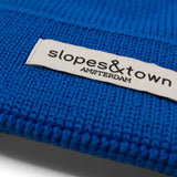 Close-up of Slopes and Town Amsterdam woven label on electric blue kids merino wool beanie