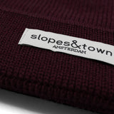 Close-up of Slopes and Town Amsterdam woven label on burgundy kids merino wool beanie