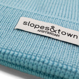 Close-up of Slopes and Town Amsterdam woven label on light blue kids merino wool beanie
