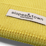 Close-up of Slopes and Town Amsterdam woven label on yellow  kids merino wool beanie