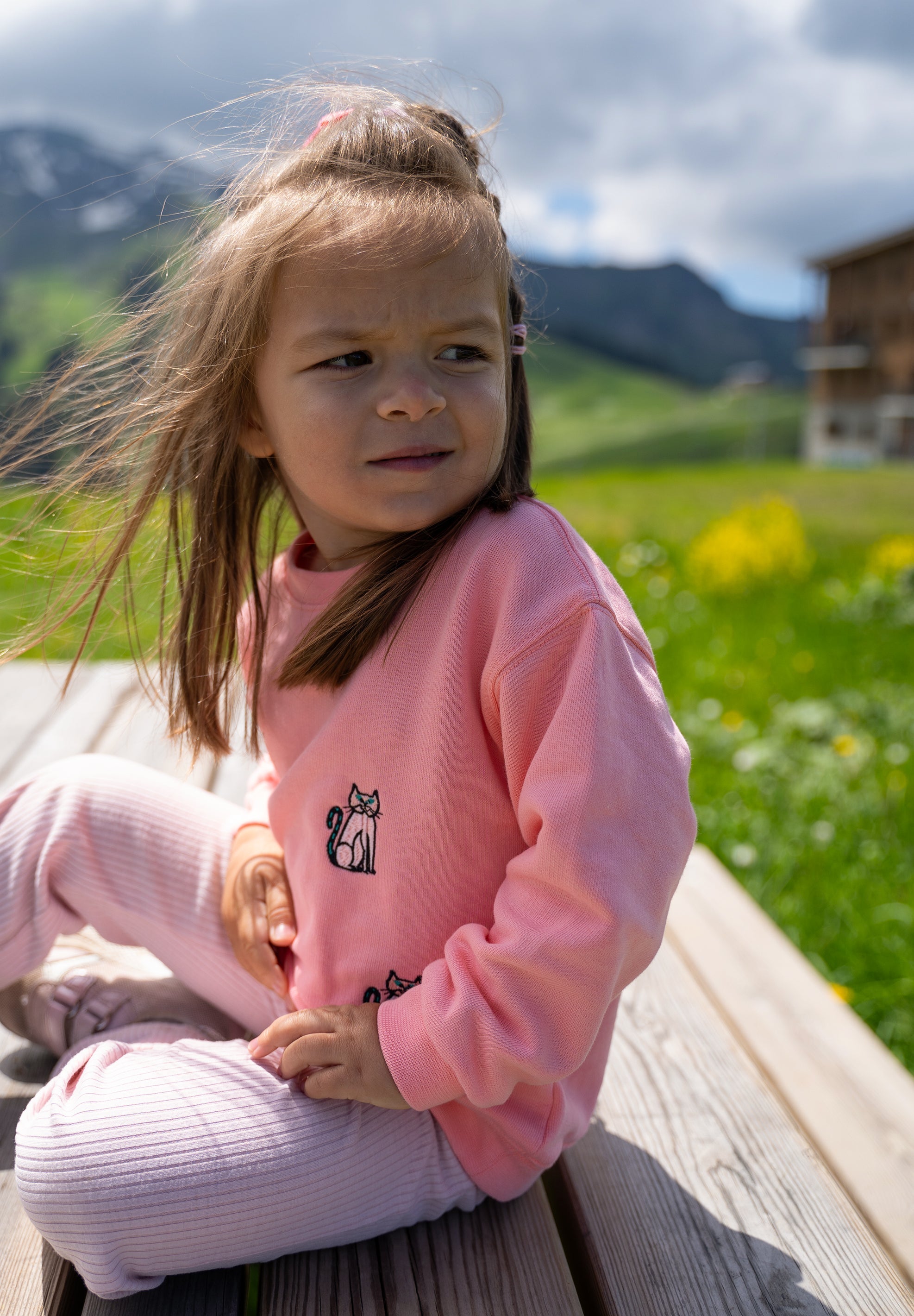 Child wearing pink organic cotton sweatshirt with embroidered cat design