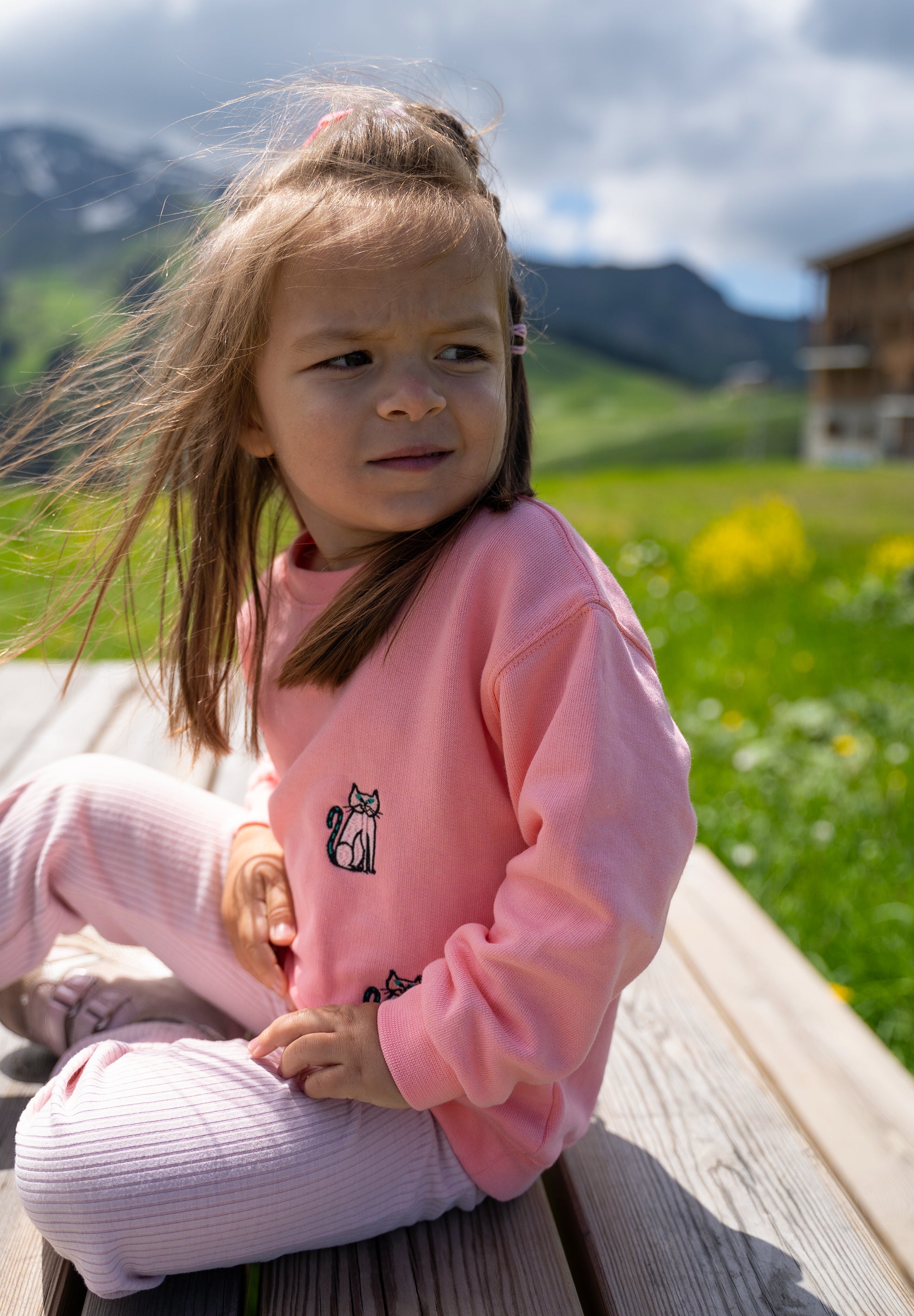 Child wearing pink organic cotton sweatshirt with embroidered cat design