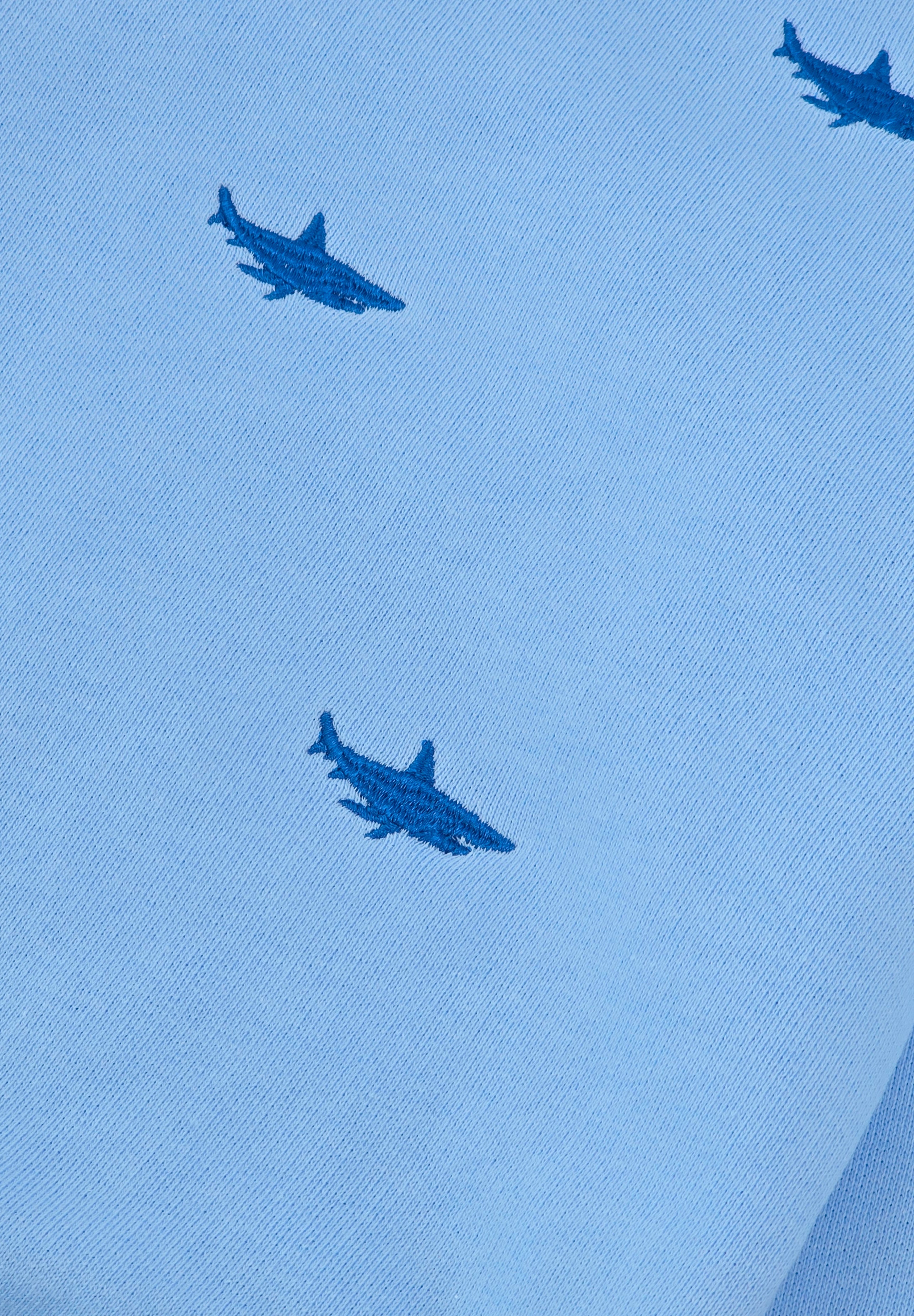 Close-up of shark embroidery on blue kids’ tracksuit