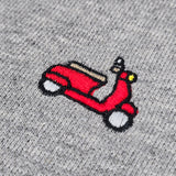 Close-up of a red embroidered vespa patch on a heather gray knit fabric background.