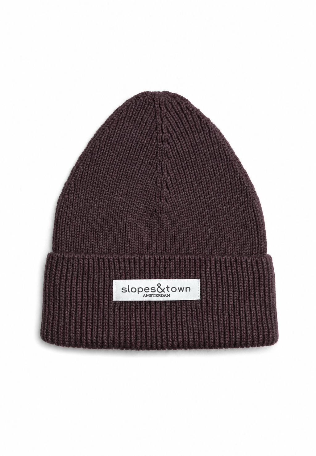 A dark brown ribbed knit beanie hat with a white rectangular brand patch on the front cuff that reads 'slopes&town AMSTERDAM'.