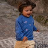 Child wearing blue organic cotton sweatshirt with airplane embroidery