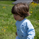 Child wearing light blue Slopes and Town kids' sweatshirt with shark design
