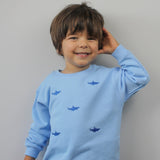 Child wearing blue tracksuit bottoms with shark embroidery