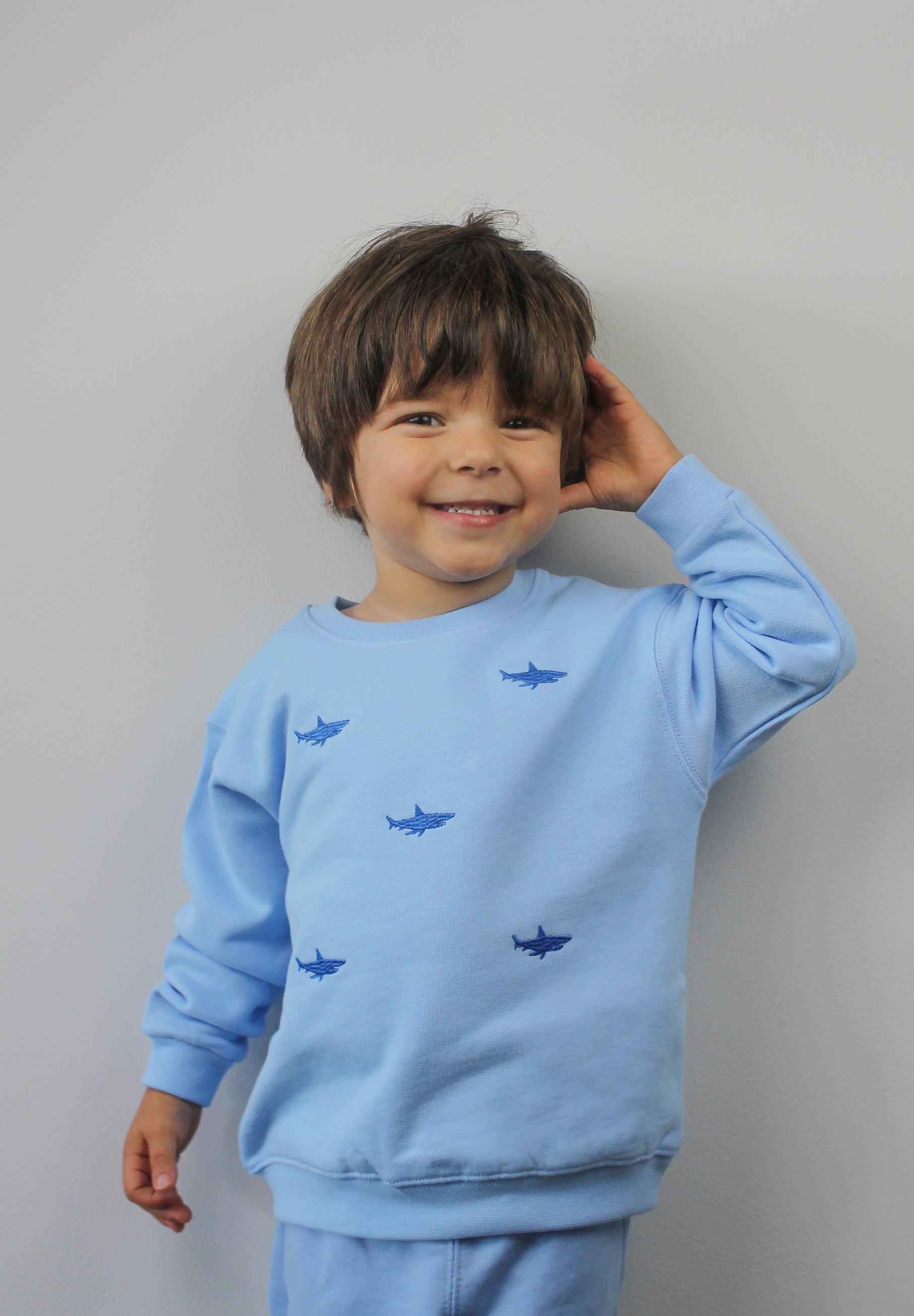 Child wearing blue tracksuit bottoms with shark embroidery
