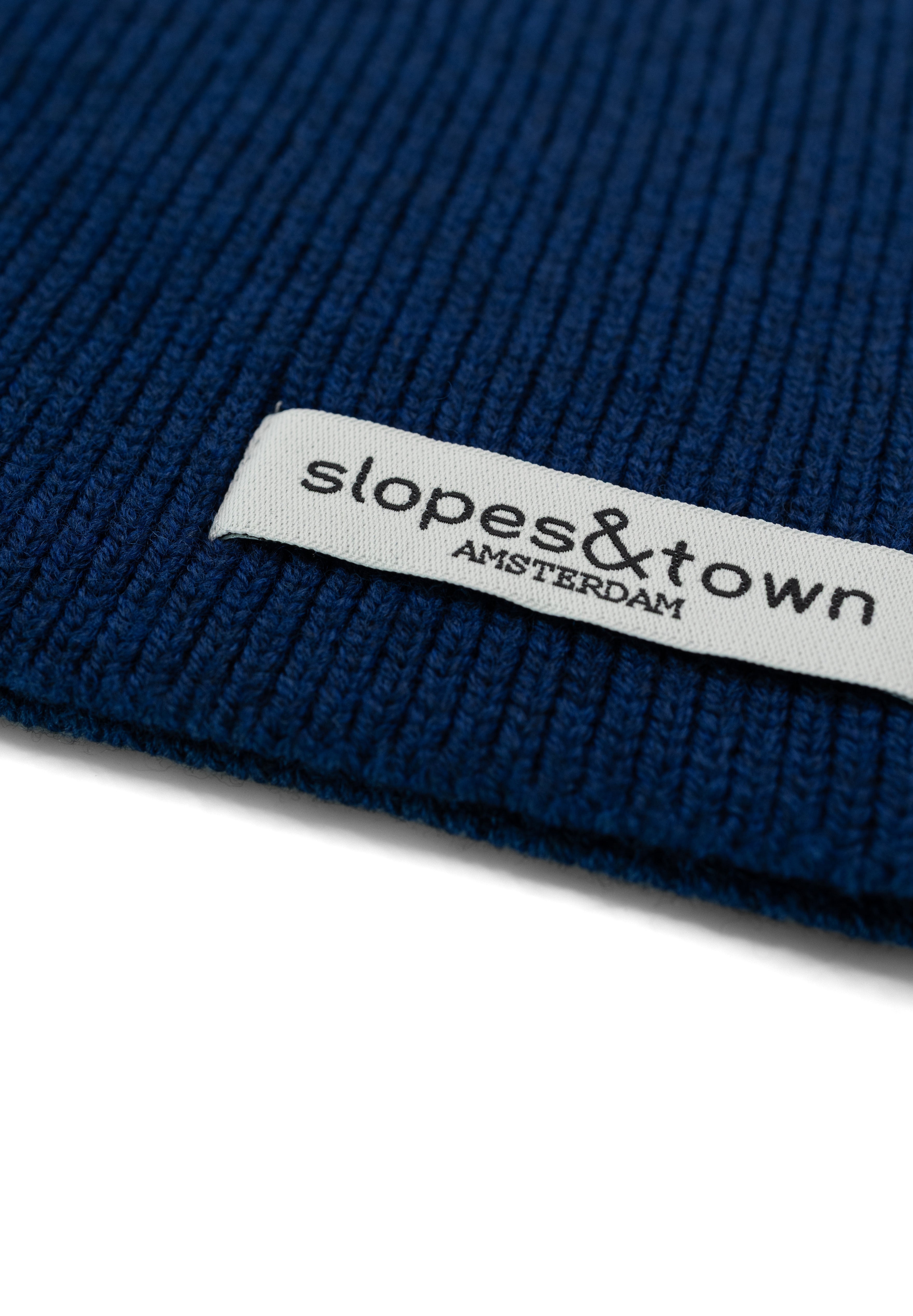 Close-up of Slopes and Town Amsterdam woven label on navy blue kids merino wool snood