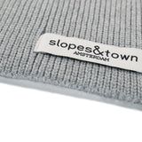 Close-up of Slopes and Town Amsterdam woven label on melange grey kids merino wool snood