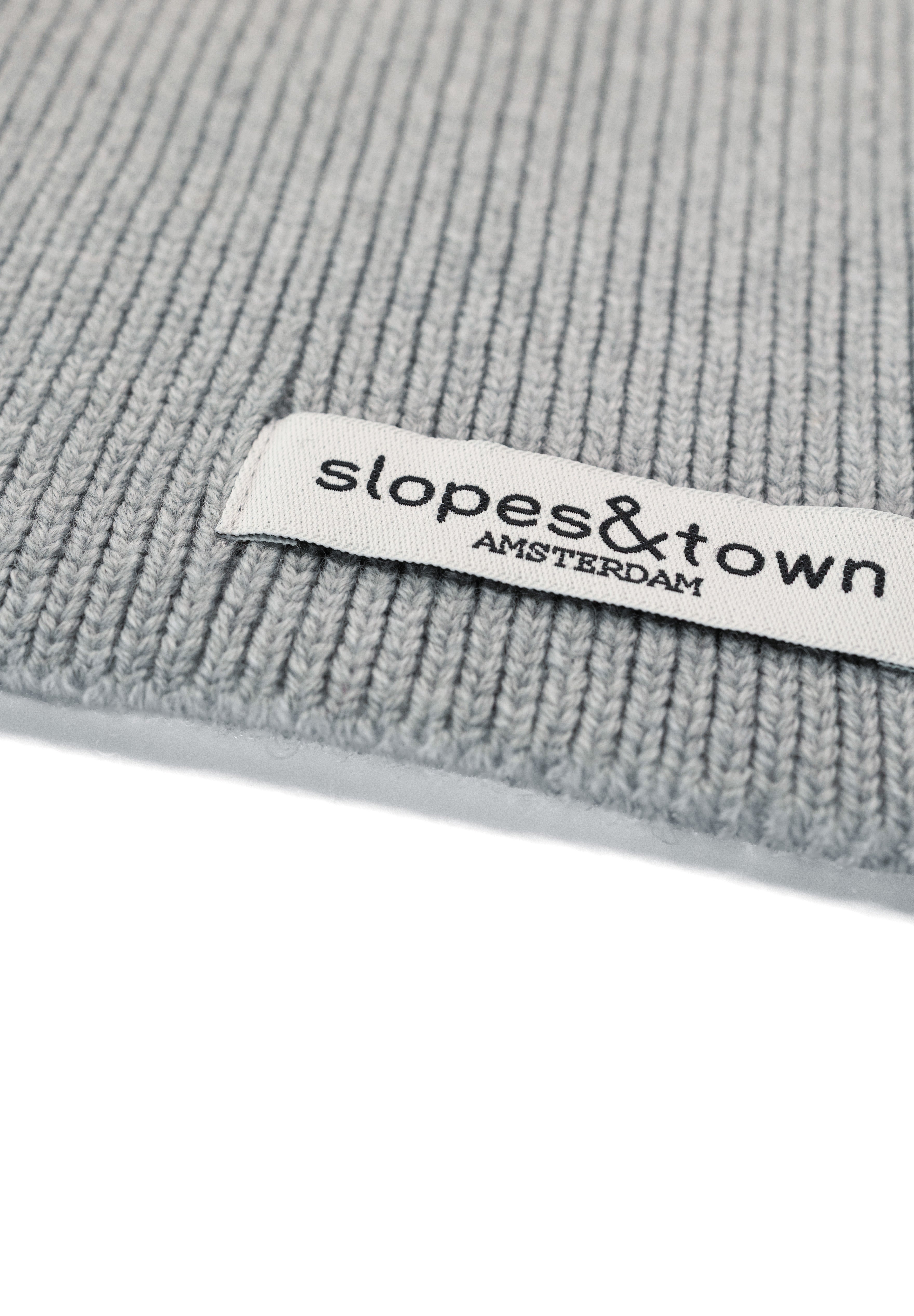 Close-up of Slopes and Town Amsterdam woven label on melange grey kids merino wool snood