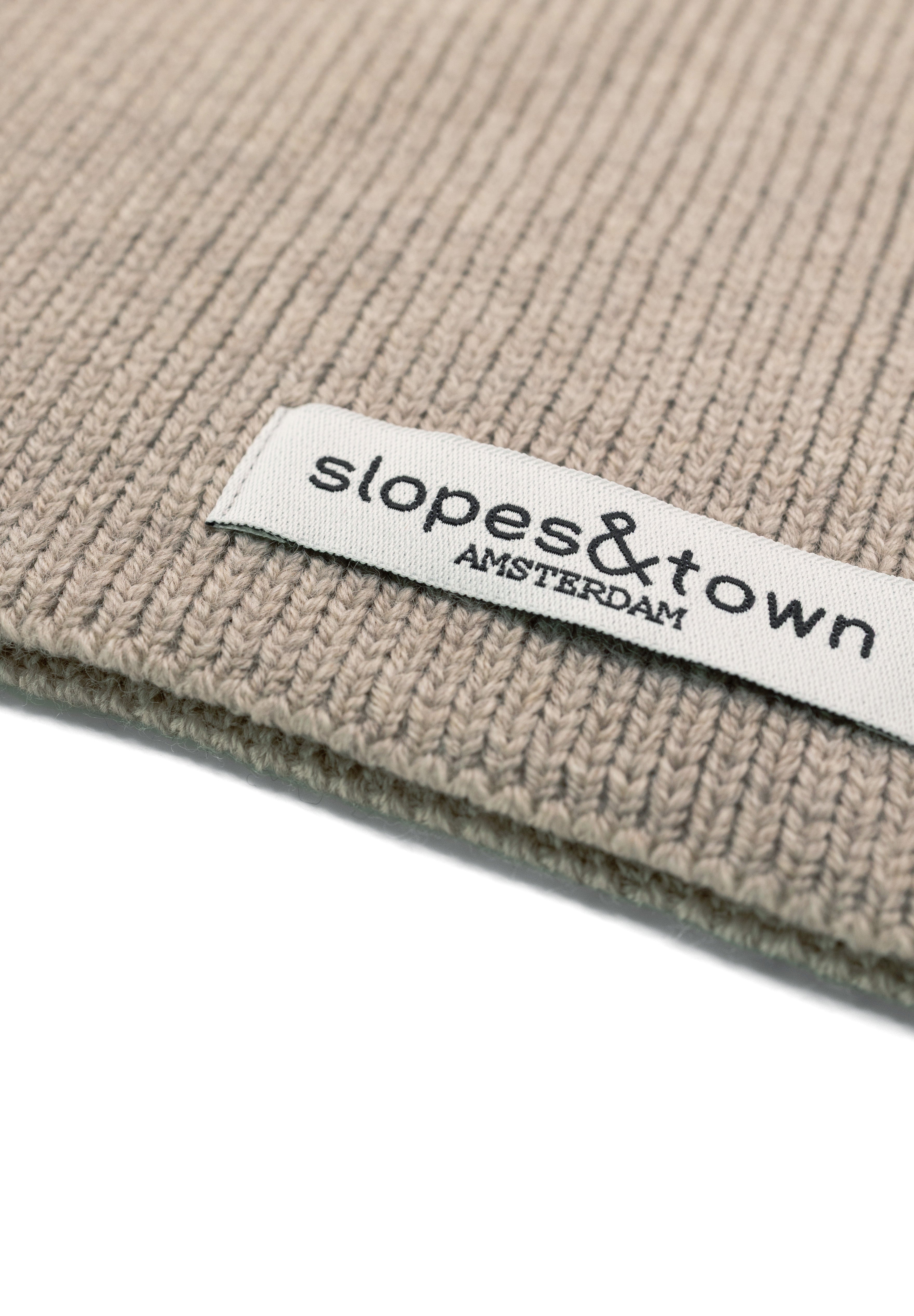 Close-up of Slopes and Town Amsterdam woven label on beige kids merino wool snood