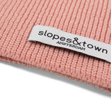 Close-up of Slopes and Town Amsterdam woven label on soft pink kids merino wool snood