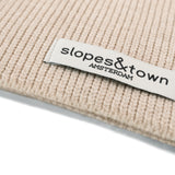 Close-up of Slopes and Town Amsterdam woven label on latte beige kids merino wool snood