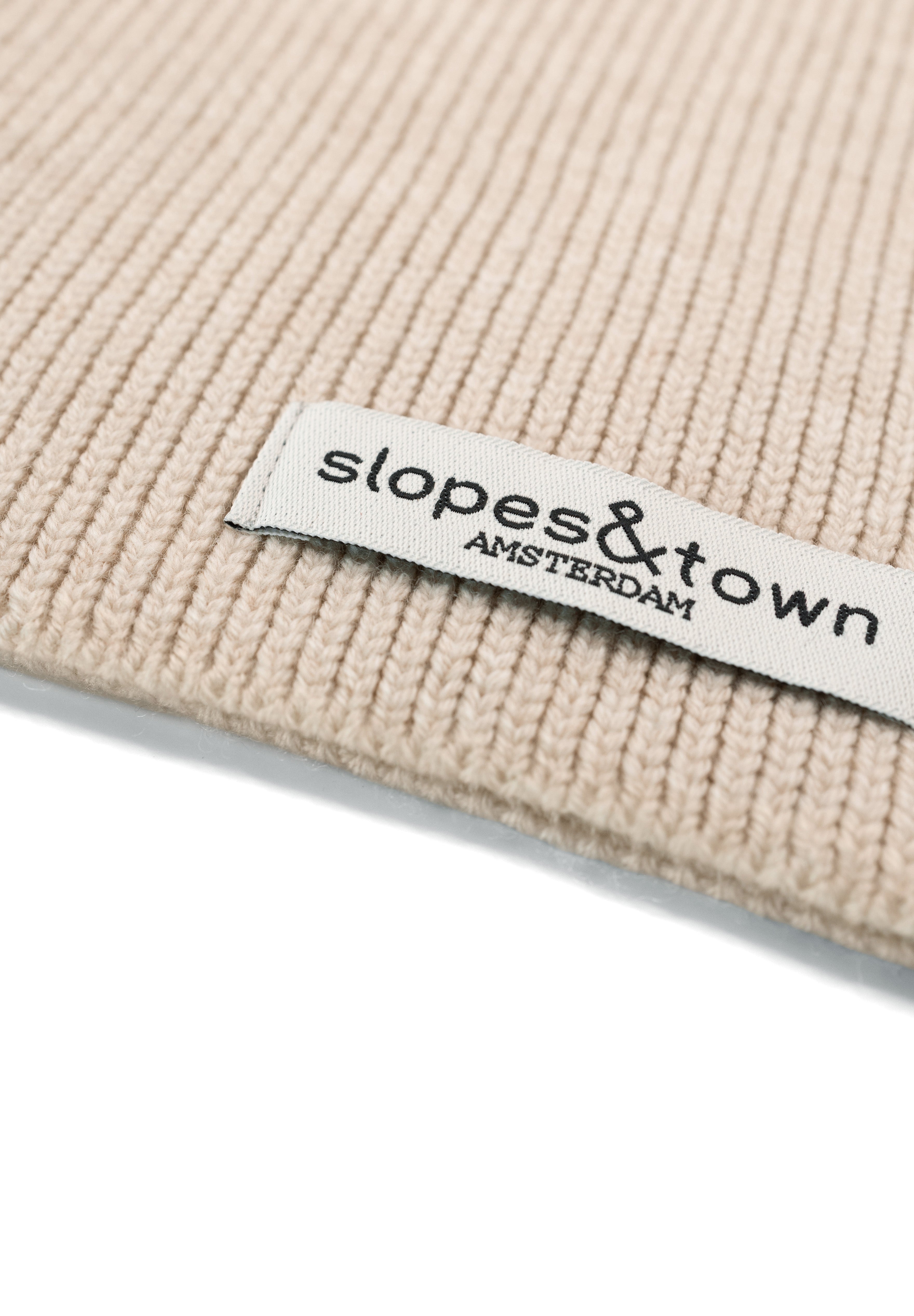 Close-up of Slopes and Town Amsterdam woven label on latte beige kids merino wool snood