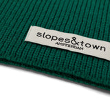 Close-up of Slopes and Town Amsterdam woven label on pine green kids merino wool snood