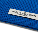 Close-up of Slopes and Town Amsterdam woven label on electric blue kids merino wool snood