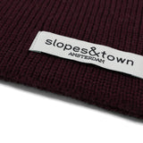 Close-up of Slopes and Town Amsterdam woven label on burgundy kids merino wool snood"