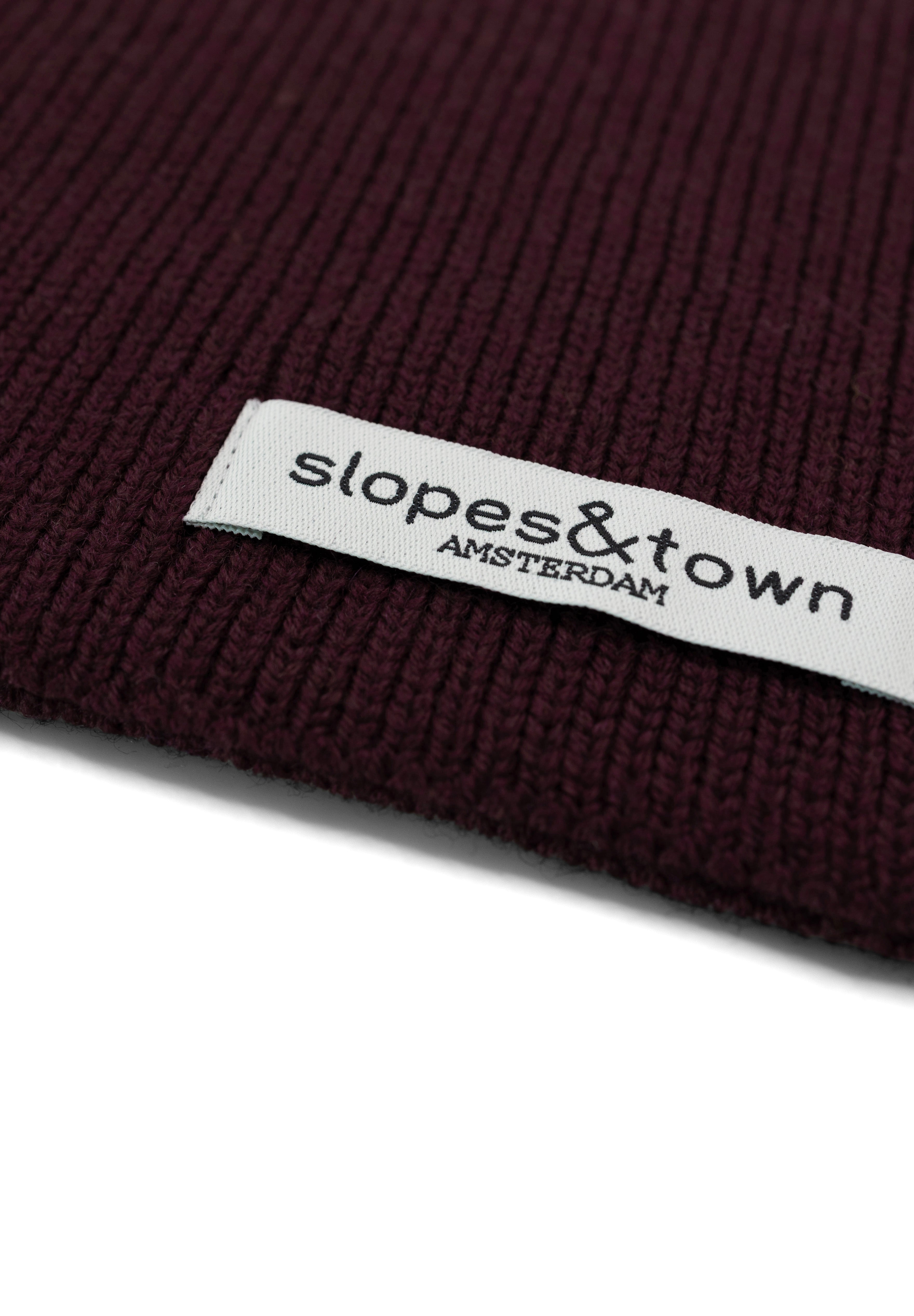 Close-up of Slopes and Town Amsterdam woven label on burgundy kids merino wool snood"