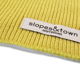 Close-up of Slopes and Town Amsterdam woven label on yellow kids merino wool snood