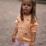 Child wearing kids' organic cotton sweatshirt with sausage dog embroidery