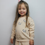 Child wearing cream tracksuit with white terrier dog embroidery