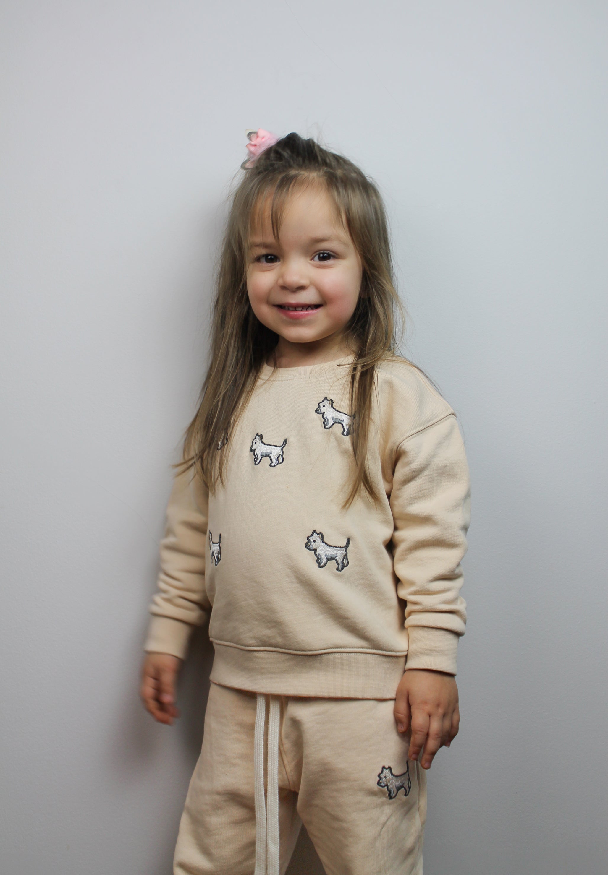 Child wearing cream tracksuit with white terrier dog embroidery